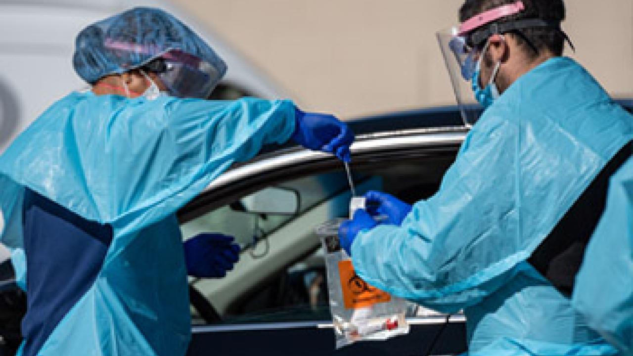 clinicians conduct COVID-19 tests at a drive-through testing site