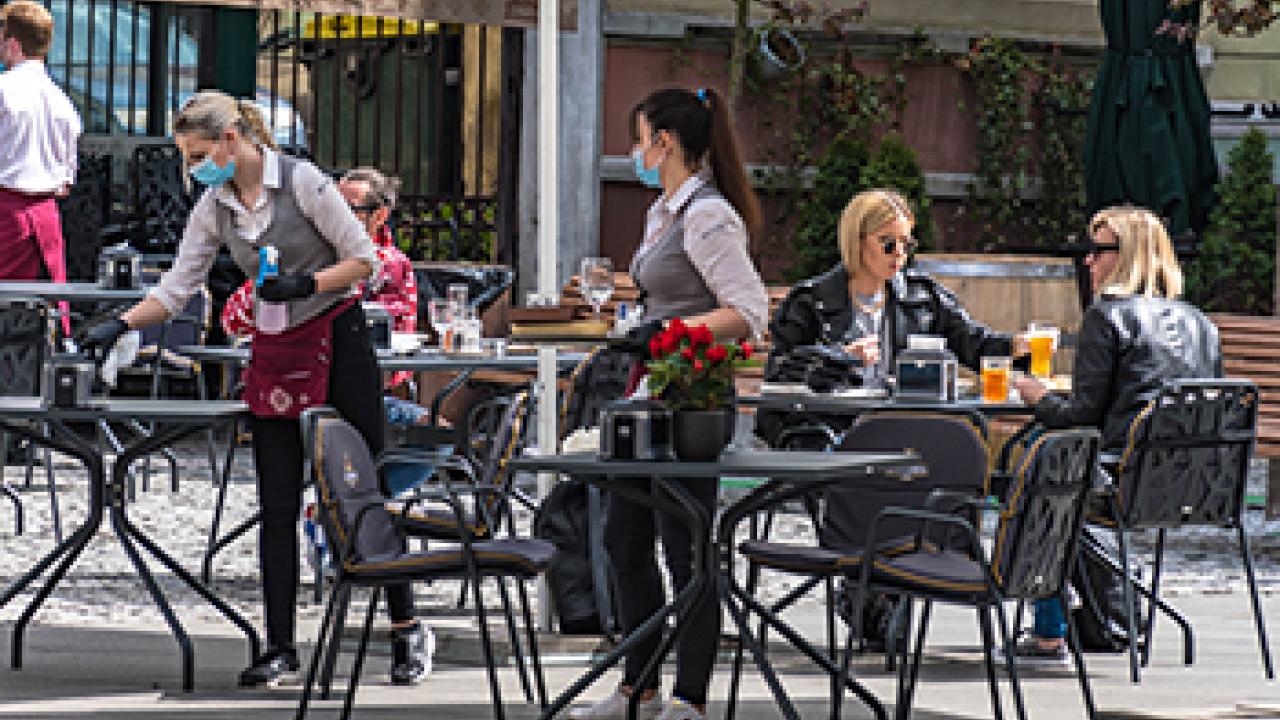 Just spraying cleaner and wiping does not protect against COVID-19. The cleaner usually requires contact time of 1 minute or more. woman cleaning an outdoor restaurant table
