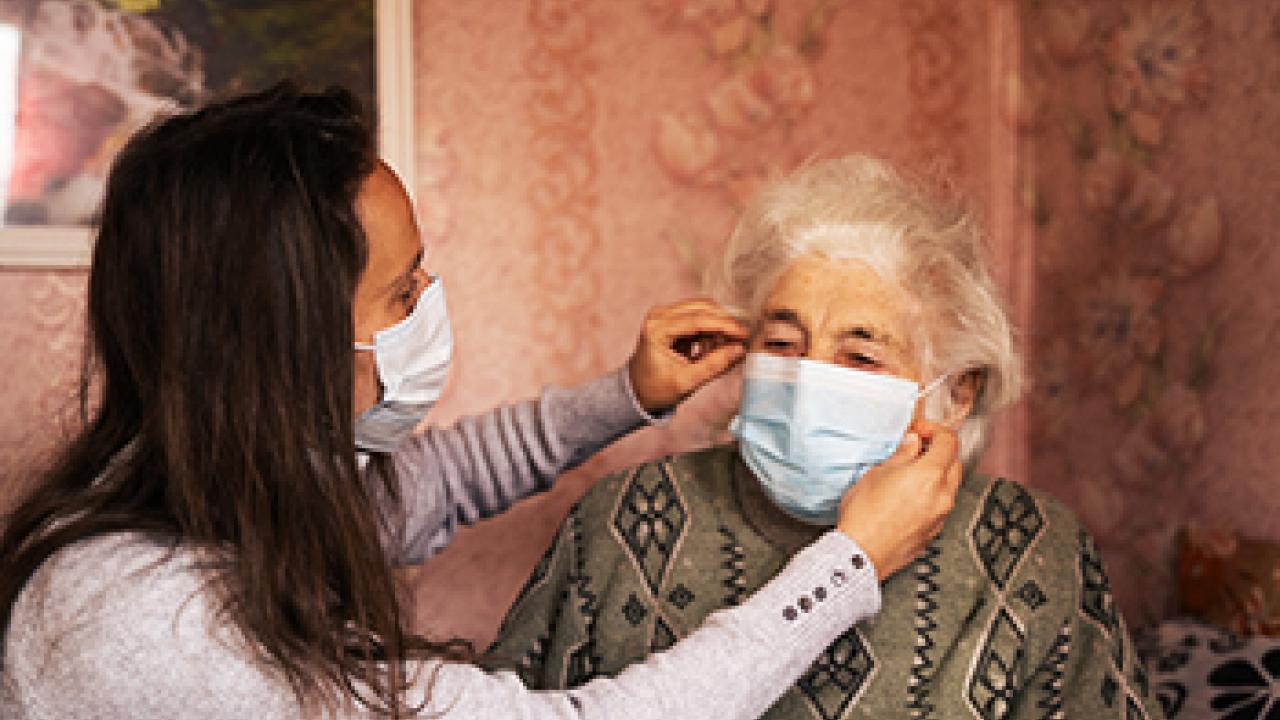 younger woman putting face mask on older woman