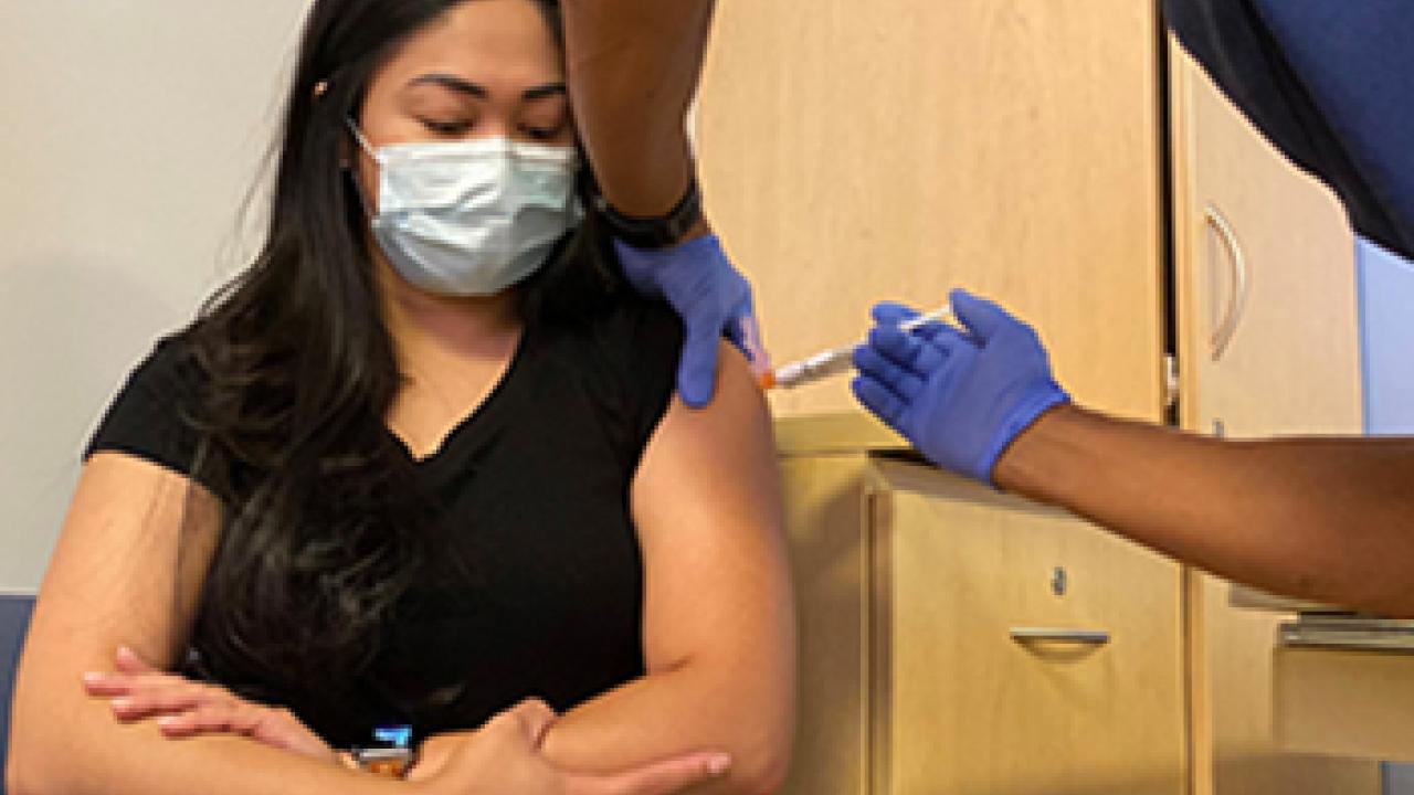 woman in mask receiving vaccine shot