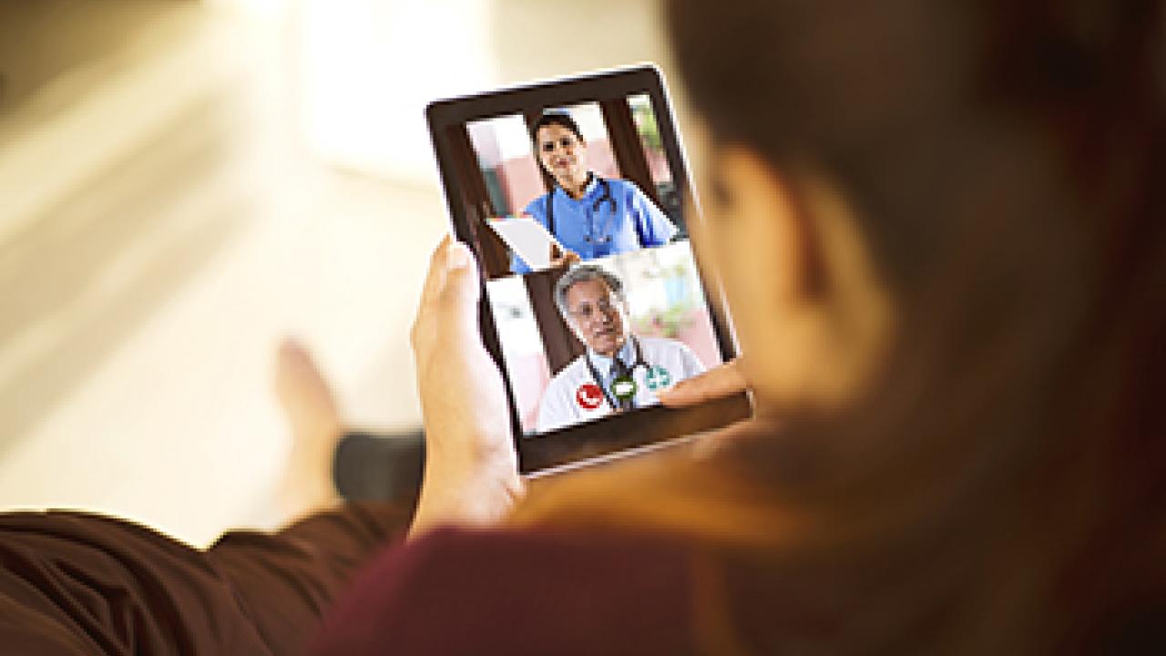 woman on tablet participating in video call with doctors