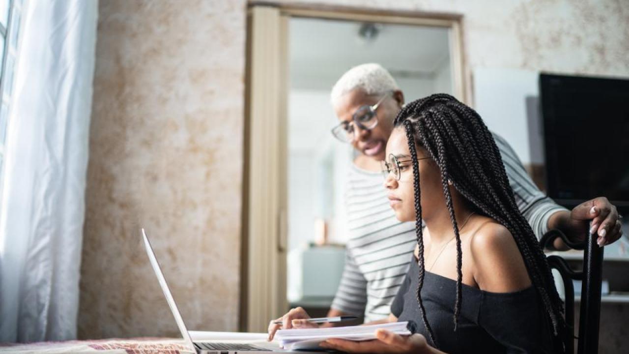 high school student looking at computer with adult