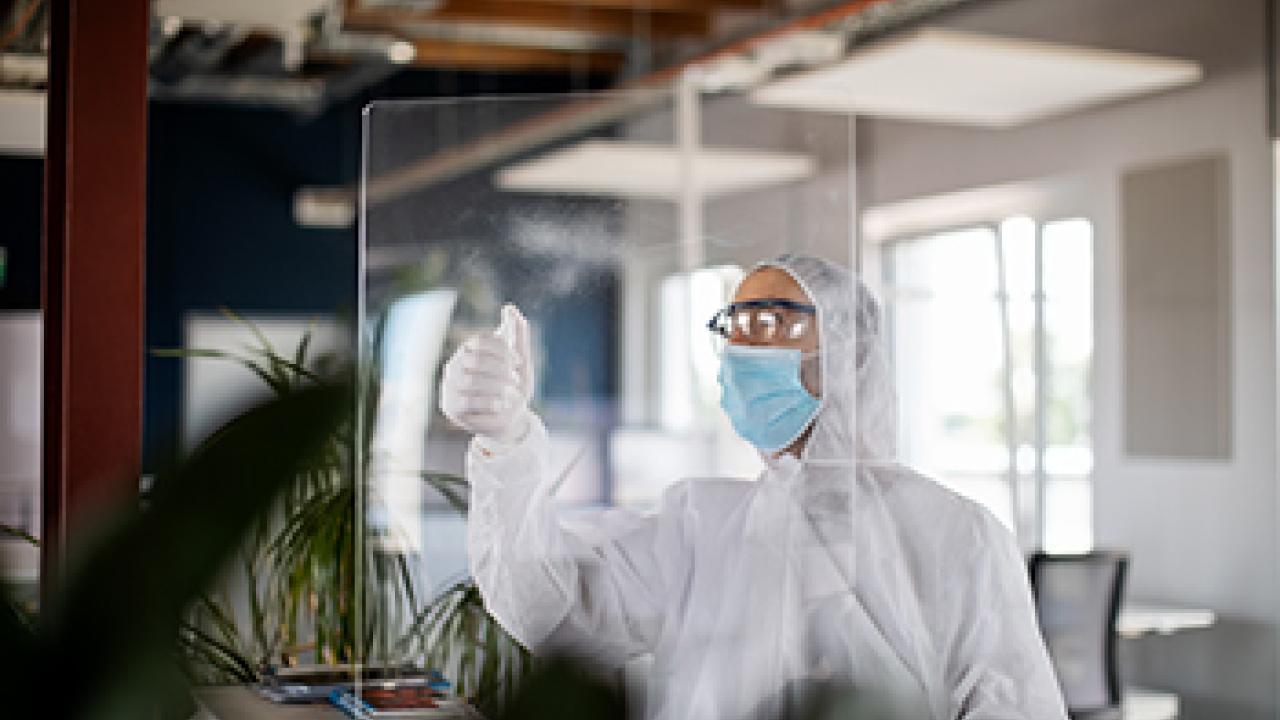 worker cleaning office wearing mask and protective gear
