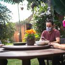 three people wearing masks sitting outside at a table